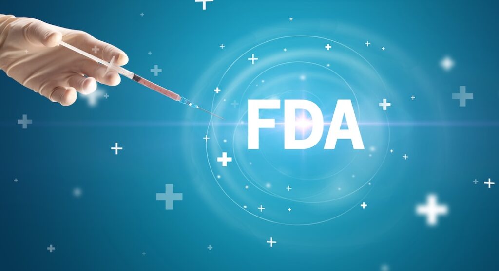 Hand holding a syringe with the letters FDA