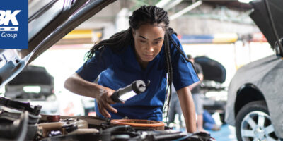 Woman mechanic looking under hood of car