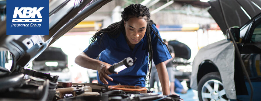 Woman mechanic looking under hood of car