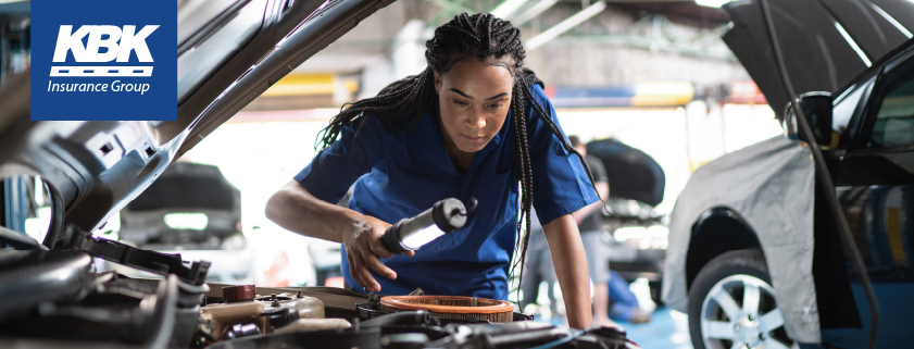 Woman mechanic looking under hood of car