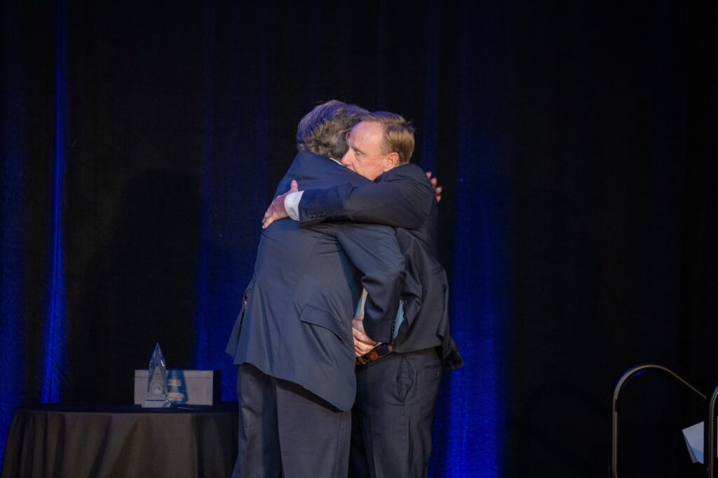 Photo of Geof McKernan hugging his brother, Bill, on stage